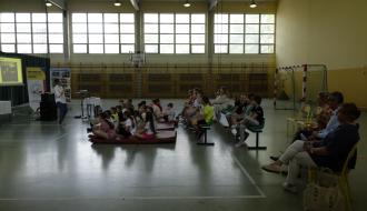 Prelekcję dotyczącą rollerów prowadzi przedstawicielka firmy Orto Med Sport w Łodzi. uczniowie trzecich klas szkół podstawowych z terenu Gminy Drzewica znajdują się w hali sportowej SP w Drzewicy przy ul. Staszica. Hala przedzielona jest kotarami, na parkiecie rozstawione rollupy promocyjne szkoły oraz firmy Orto Med. Sport w Łodzi. 