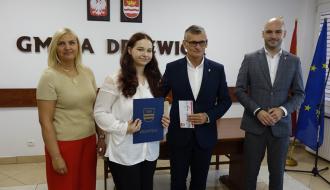 Z rąk Burmistrza Drzewicy Janusza Reszelewskiego stypendium odbiera Hanna Beeger. Obok (po lewej) Dyrektor ZEAS w Drzewicy Agnieszka Kwiecień i (po prawej) Zastępca Burmistrza Drzewicy Dominik Niemirski.