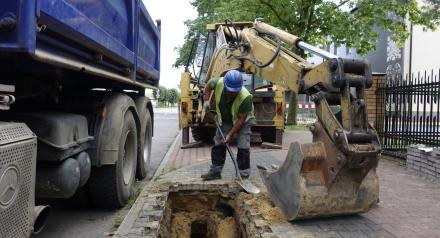 robotnik kopie dół po wyjęciu cegieł z chodnika 