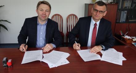 Dwóch mężczyzn podpisujących przy biurku umowę na dostawę i montaż instalacji solarnych