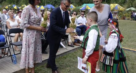 Przewodnicząca Rady Miejskiej w Drzewicy Dorota Wiktorowicz i Burmistrz Drzewicy Janusz Reszelewski odbierają od dzieci bukiet zbóż. Obok Dyrektor RCK w Drzewicy Alina Szymańska