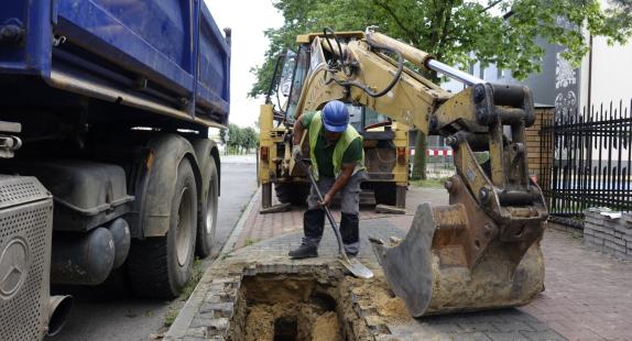 robotnik kopie dół po wyjęciu cegieł z chodnika 
