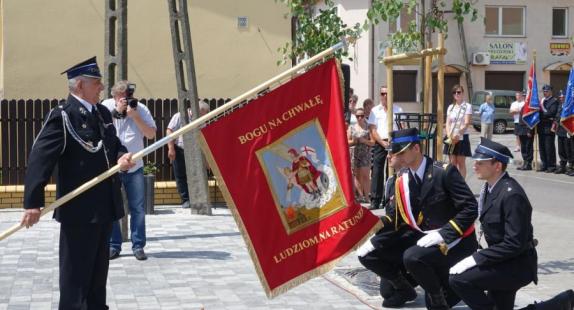 członkowie jednostki OSP klęczą przed sztandarem trzymanym przez dowódcę podczas uroczystości stulecia OSP
