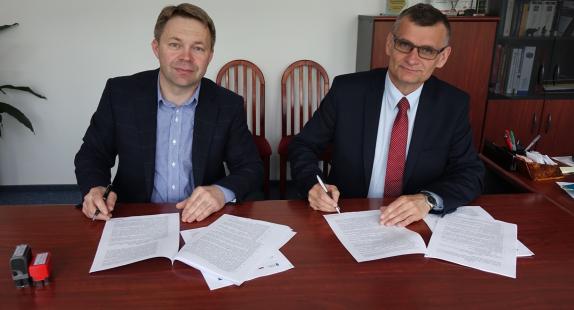 Dwóch mężczyzn podpisujących przy biurku umowę na dostawę i montaż instalacji solarnych