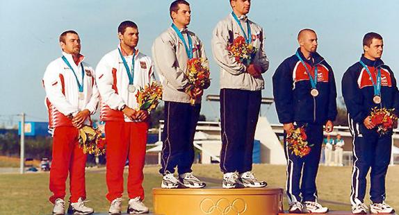 kajakarze stoją na podium z medalami i kwiatami