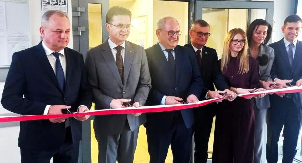 Symbolicznego przecięcia wstęgi dokonuje siedem osób - od lewej: Członek Zarządu Województwa Łódzkiego Artur Ostrowski, II Wicewojewoda Łódzki Grzegorz Majewski, I Wicewojewoda Łódzki Marek Mazur, Burmistrz Drzewicy Janusz Reszelewski, p.o. Zastępcy Dyrektora Wojewódzkiego Urzędu Pracy w Łodzi Aneta Dziemdziela, Przewodnicząca Rady Miejskiej w Drzewicy Dorota Wiktorowicz oraz p.o. Zastępcy Dyrektora Regionalnego Centrum Polityki Społecznej w Łodzi Oskar Kuliński.