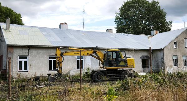  Żółta koparka Komatsu zaparkowana przed starym budynkiem „Ceglanki”.